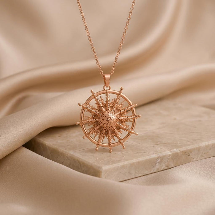 Achernar Star Pendant Necklace in Rose Gold Plated displayed on a pale stone block with beige draped fabric