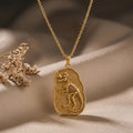 Gold Plated Silver Albertosaurus fossil pendant with raised dinosaur skeleton on textured plaque over beige satin beside dried flowers