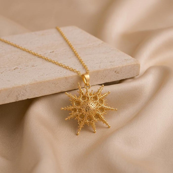 Gold Plated Silver Alkaid star necklace draped across a rectangular stone slab, with the pendant resting on champagne satin