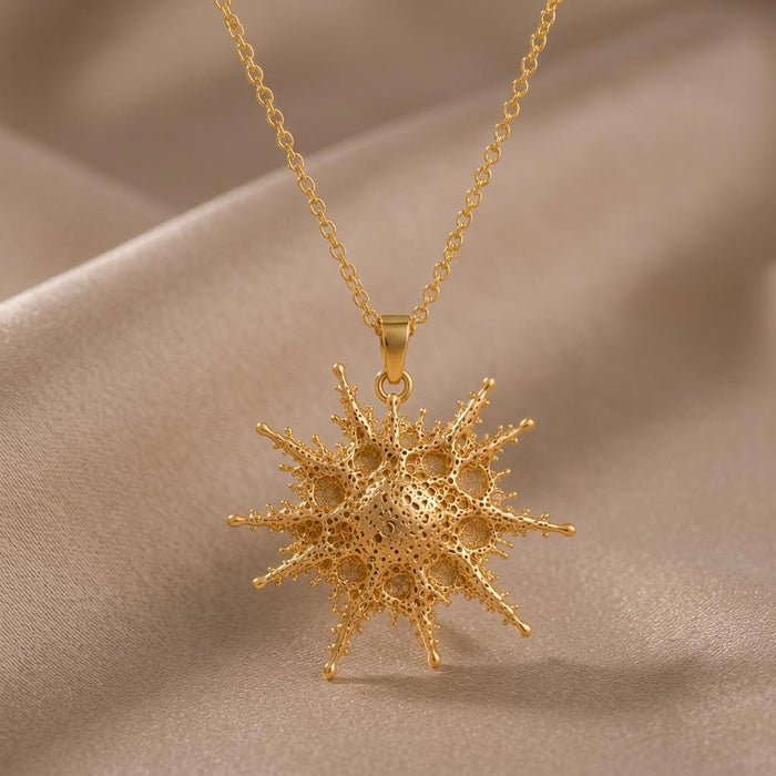 Front close-up of the Gold Plated Silver Alkaid pendant suspended above champagne satin, showing its perforated center and rounded rays