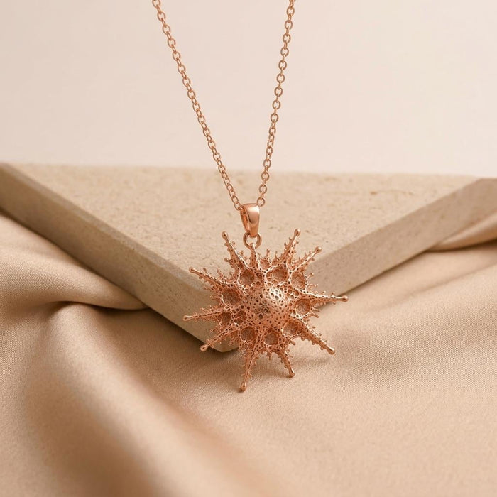 Rose Gold Plated Alkaid star necklace hanging beneath the corner of an angled stone slab on champagne satin