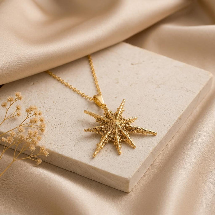 Gold Plated Silver Altair multi-point pendant necklace on a stone block with dried flowers