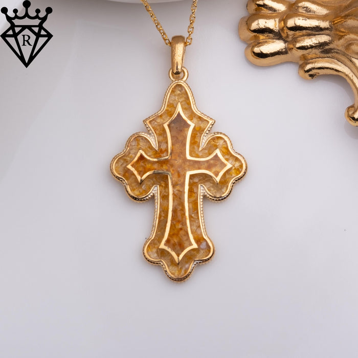 Front view of the amber-colored cross pendant with a scalloped edge and raised metal outline