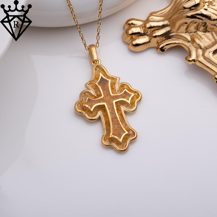 Cross pendant hanging from a gold-finish chain beside an ornate decorative corner