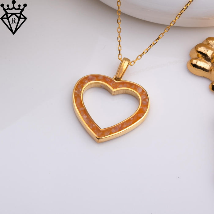 Angled tabletop product photograph of an amber-colored open heart pendant