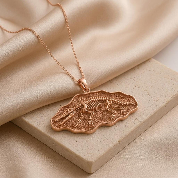 Rose Gold Plated Ambulocetus Fossil Pendant displayed on a stone block and beige fabric