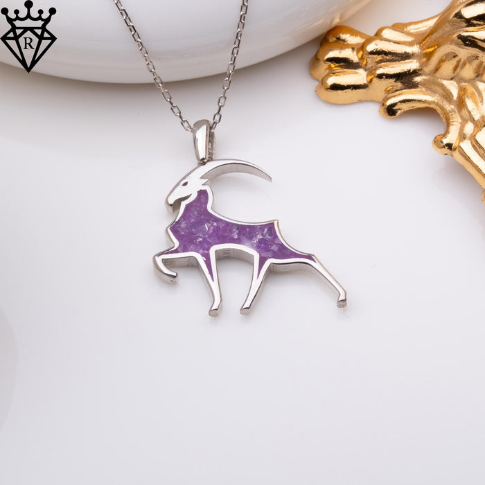 Front-facing zodiac pendant hanging from a silver chain, with the horn curving over its back