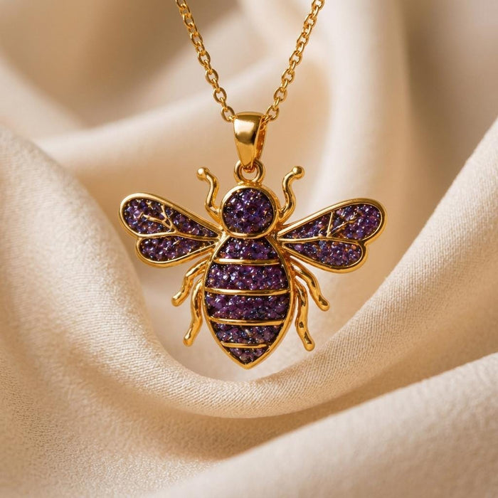 Gold Plated Silver Amethyst Druzy Bee Necklace with purple textured wings and segmented abdomen on ivory fabric