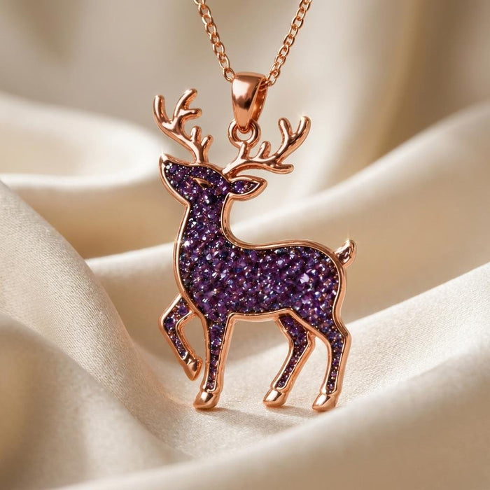 Rose-toned deer pendant with textured purple center displayed on cream satin