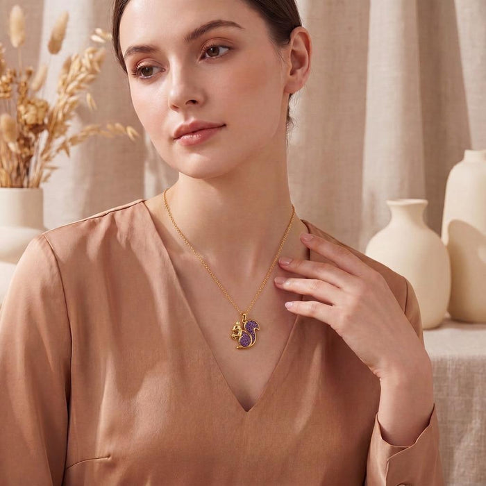 Model wearing a Gold Plated Silver squirrel snack pendant necklace with textured purple druzy detail and a satin blouse