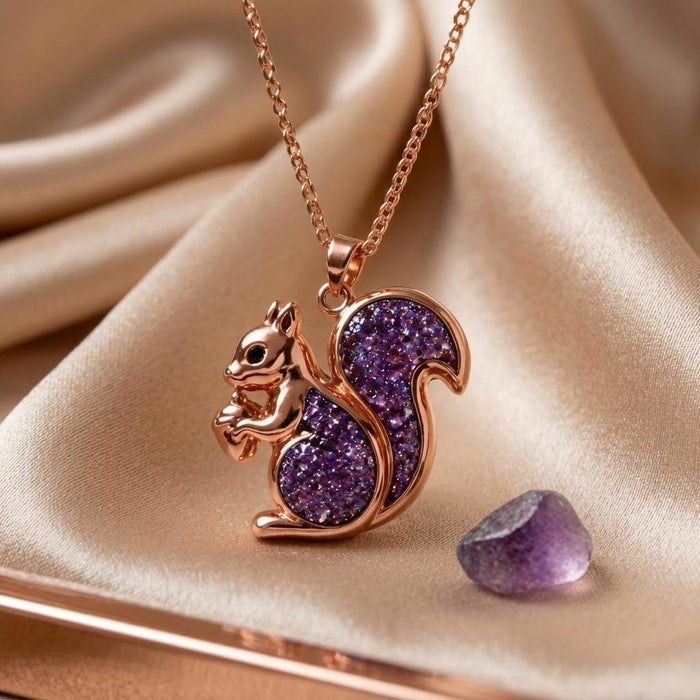 Rose-toned squirrel snack pendant necklace on champagne satin beside a loose purple stone