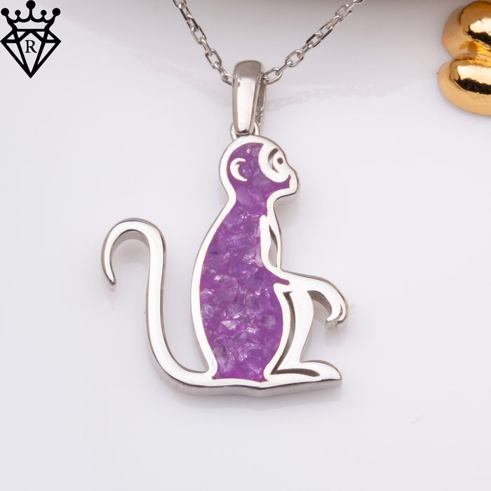 Front view of a seated monkey pendant with a purple center on a white background