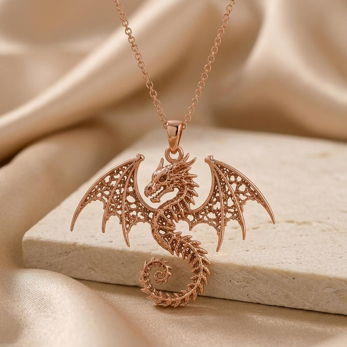 Rose-toned Ancient Dragon Fossil pendant displayed on a textured stone platform and satin