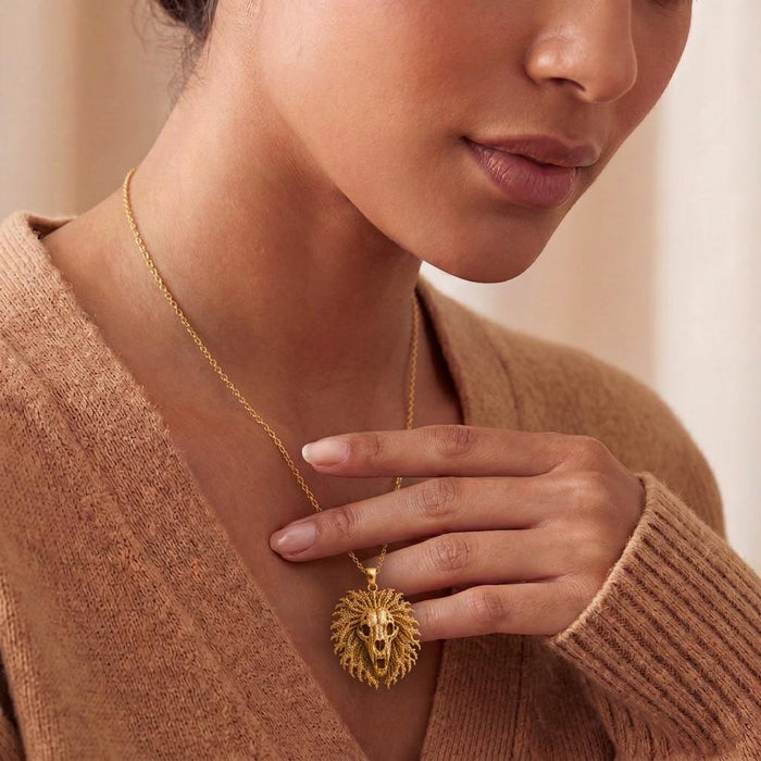Gold Plated Silver lion skull crest pendant held near a model's neckline