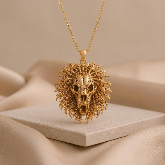 Front view of Gold Plated Silver Ancient Lion Skull Crest Necklace on a pale stone platform
