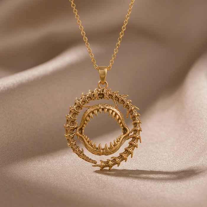 Gold Plated Silver Ancient Shark Jaw Pendant Necklace with an open tooth-lined jaw and fossil-inspired outer ring on champagne satin