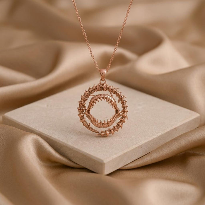 Rose Gold Plated Ancient Shark Jaw Pendant Necklace displayed on a square stone block with draped satin