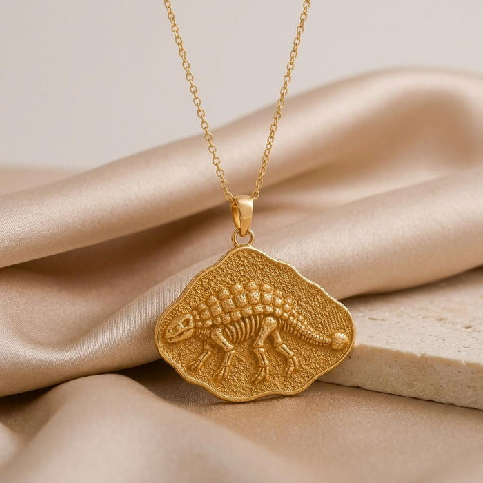 Close view of a Gold Plated Silver raised Ankylosaurus skeleton pendant on champagne satin