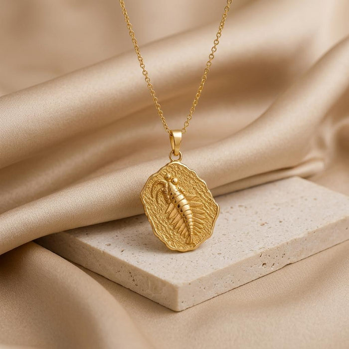 Gold Plated Silver Anomalocaris fossil medallion necklace on a pale stone slab
