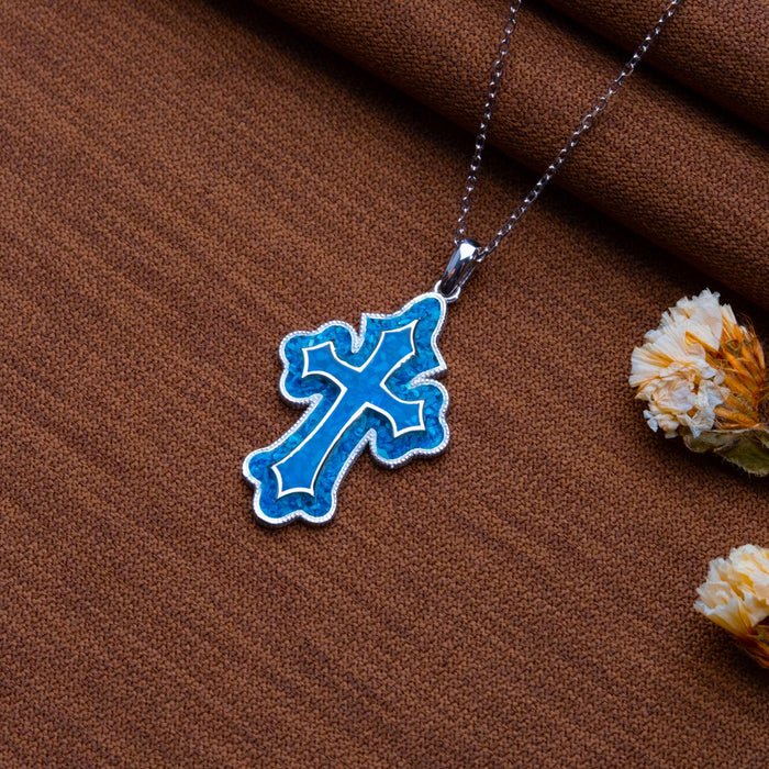 Blue Azurite cross pendant necklace on brown textured fabric with dried flowers