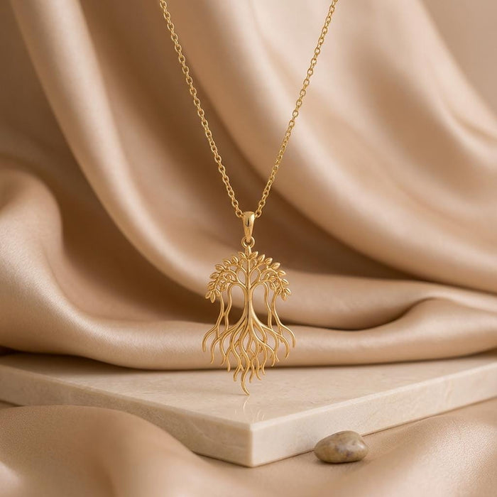 Gold Plated Silver Banyan Flow Necklace with a branching canopy and flowing roots above a stone display