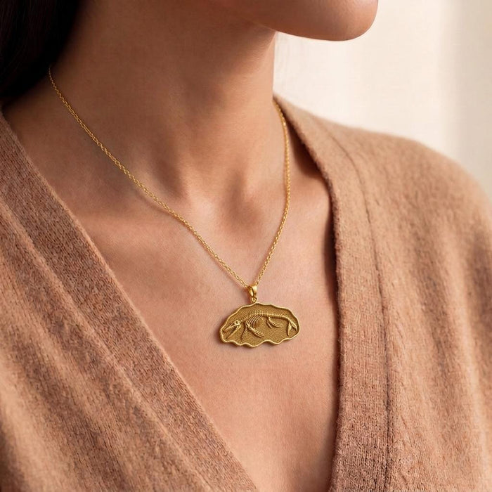 Close view of a model wearing a Gold Plated Silver Basilosaurus fossil pendant necklace with a V-neck knit top
