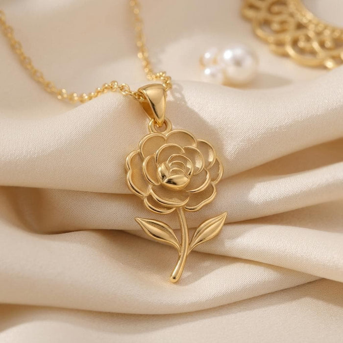Gold Plated Silver Camellia Flower Necklace with layered petals and two leaves displayed on cream satin