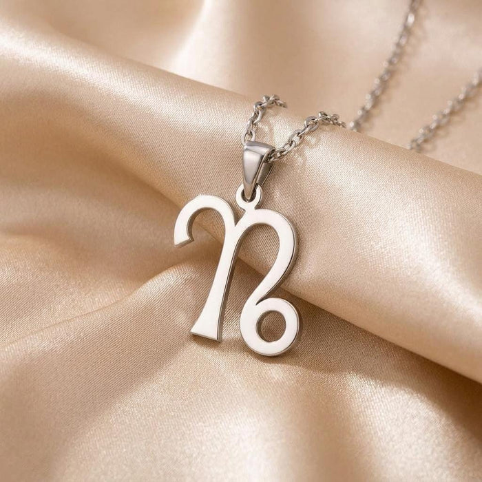 Close-up of a polished Capricorn glyph pendant with a tapered bail on champagne satin