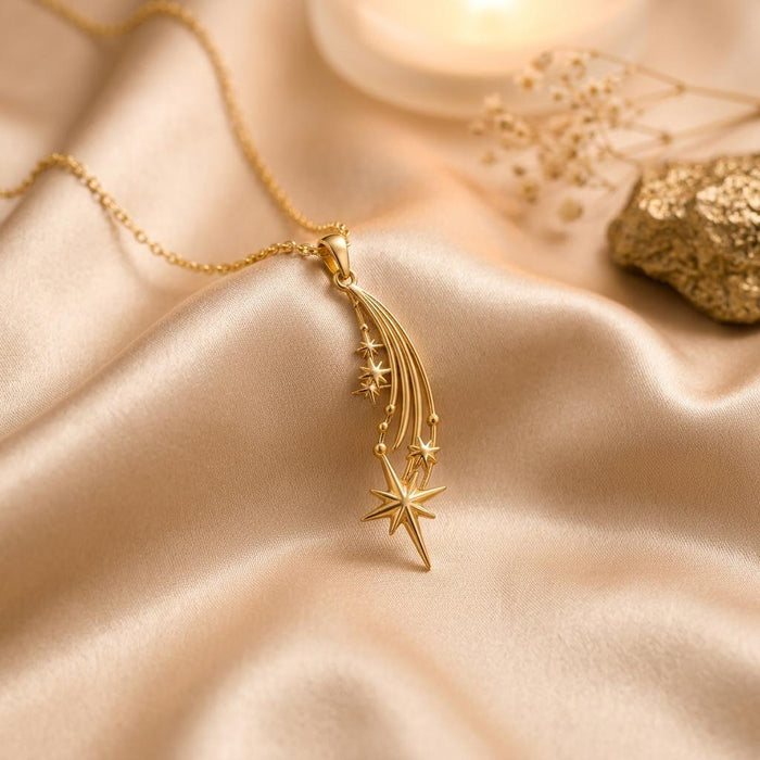 Gold Plated Silver Falling Star Pendant Necklace with three curved star trails and a pointed star drop on champagne satin