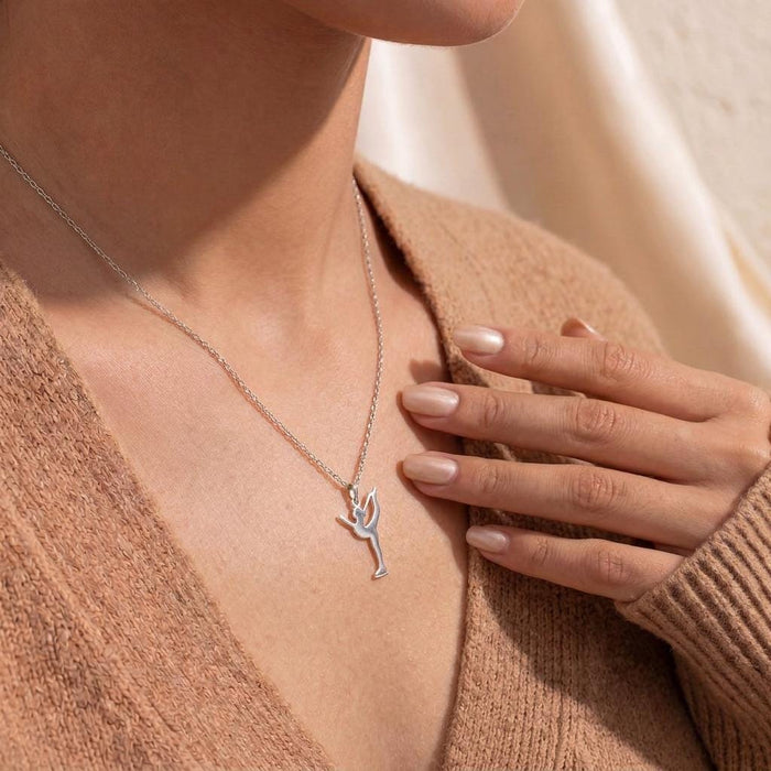Catch-foot figure skater pendant with a bent raised leg worn over a textured brown knit