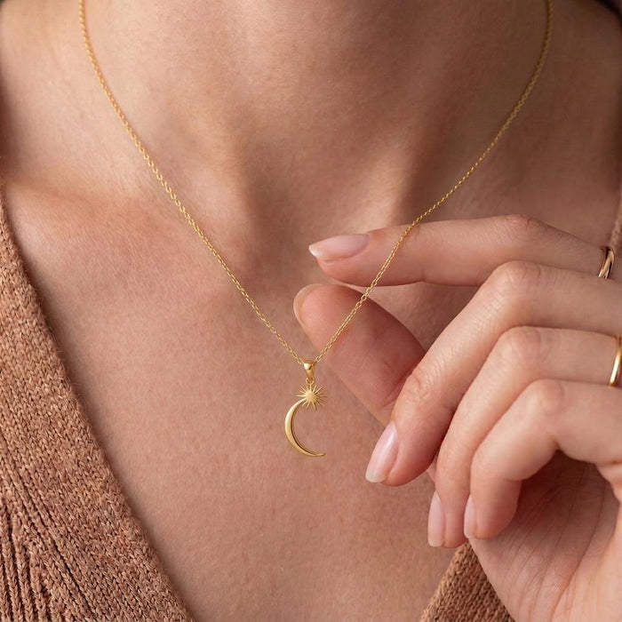 Gold Plated Silver Celestial Crescent Star Necklace worn at the neckline with a hand beside the pendant