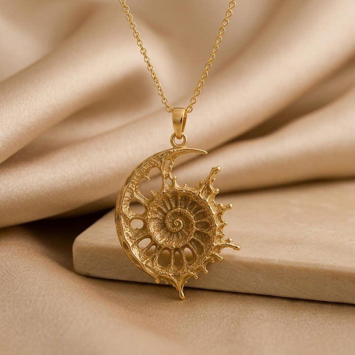 Gold Plated Silver Celestial Fossil Pendant Necklace with an ammonite-inspired spiral, open crescent, and radiating sun-ray edge on champagne satin