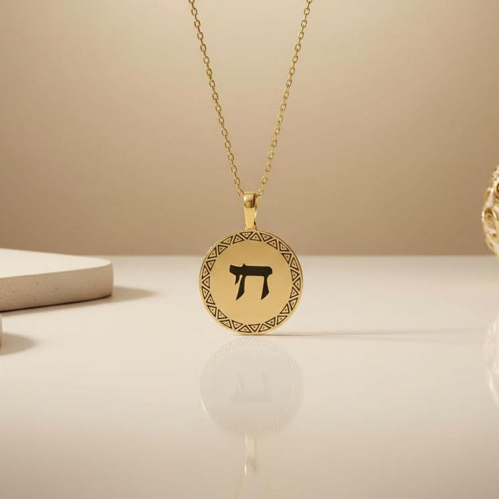 Gold Plated Silver Chai medallion necklace displayed on a reflective cream surface