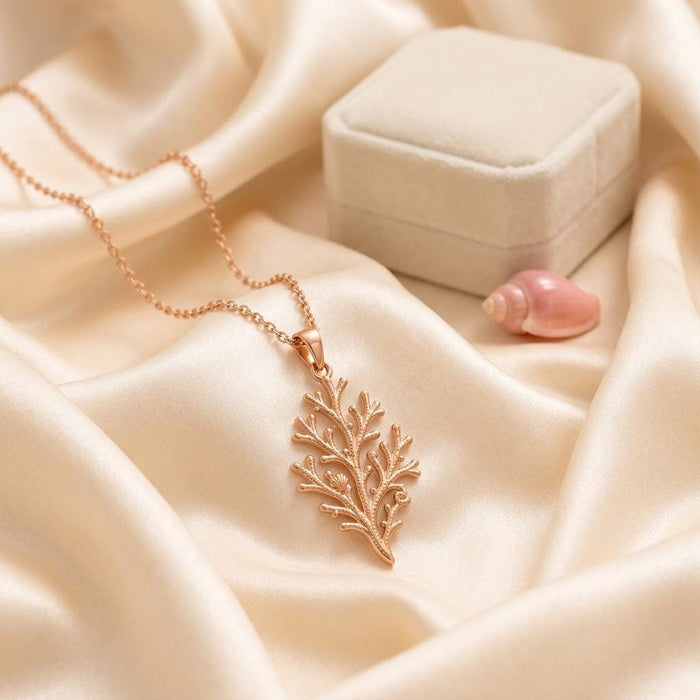 Rose Gold Plated Coral Branch Pendant Necklace displayed on satin beside a closed jewelry box and shell