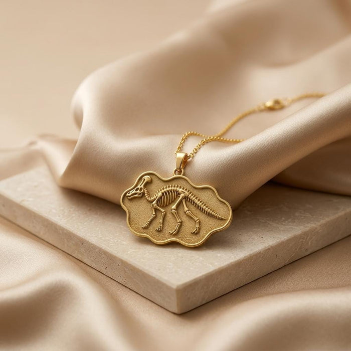 Gold Plated Silver Corythosaurus fossil pendant necklace on champagne satin and a pale stone slab