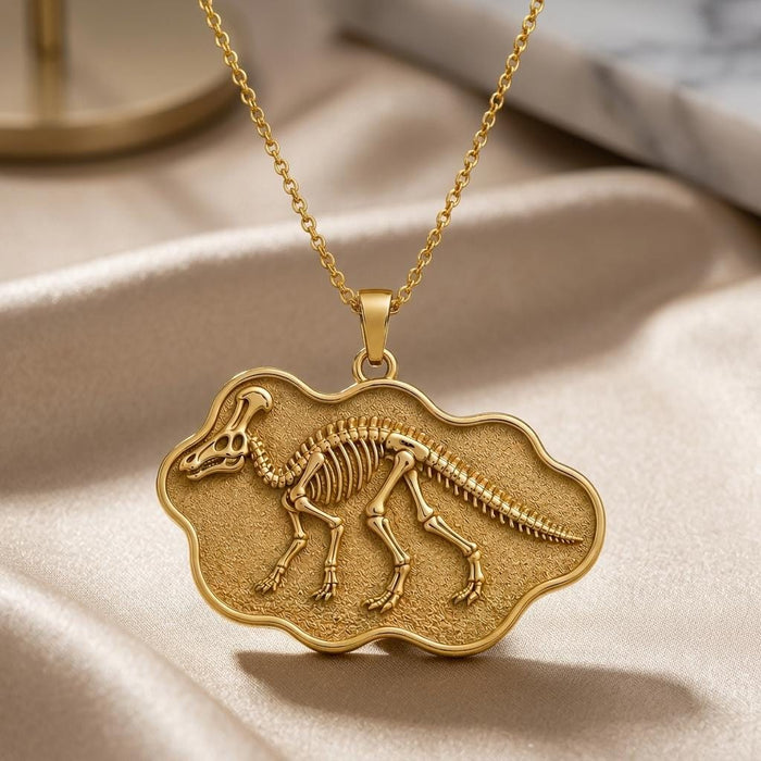 Close-up of a Gold Plated Silver Corythosaurus skeleton pendant with raised skeletal relief and textured background