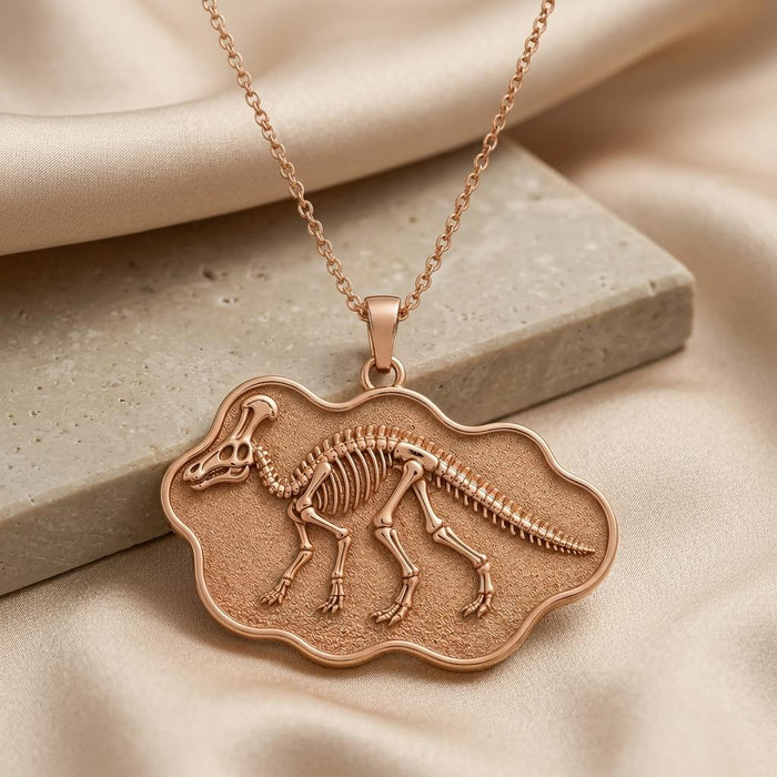 Rose Gold Plated Corythosaurus fossil pendant necklace on satin beside a pale stone block