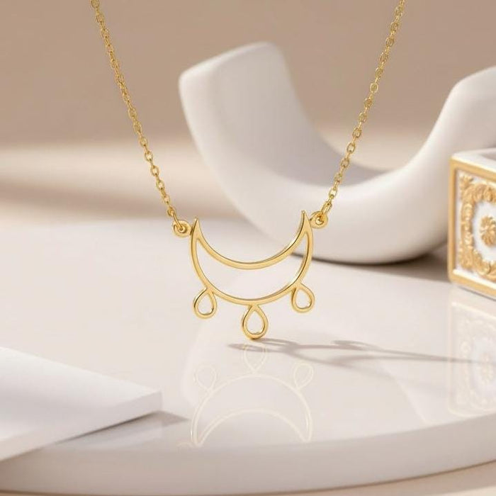 Gold Plated Silver Crescent Moon Necklace with three teardrop dangles displayed on a white surface