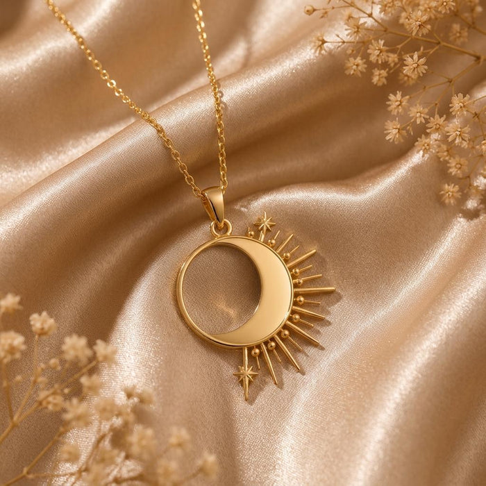 Gold Plated Silver Solar Eclipse Necklace with a side crescent, radiant rays, and star details on champagne satin beside dried flowers