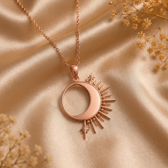 Rose-tone Solar Eclipse Necklace with an open circular center, side crescent, and radiant rays on champagne satin