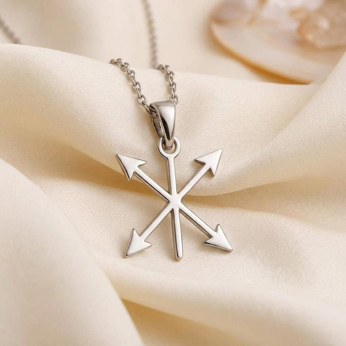 Close-up of the polished four-arrow crossed pendant on ivory satin