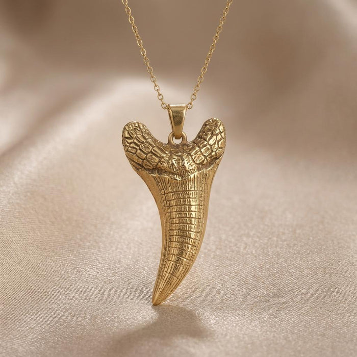 Gold Plated Silver Dakosaurus tooth pendant necklace with textured upper section on champagne satin