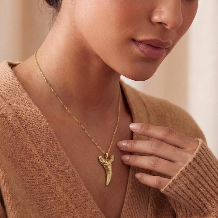 Gold Plated Silver Dakosaurus tooth pendant necklace worn with a neutral knit top