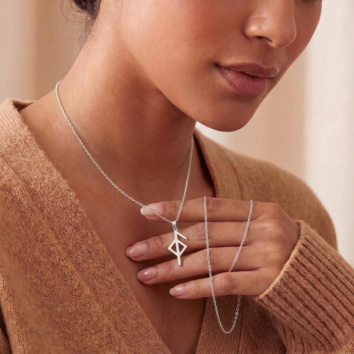 Model holding a Silver Health Rune pendant necklace at the neckline