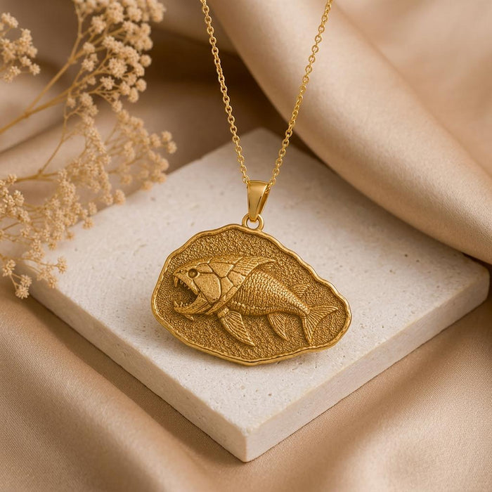 Gold Plated Silver Dunkleosteus fossil pendant necklace displayed on a light stone block