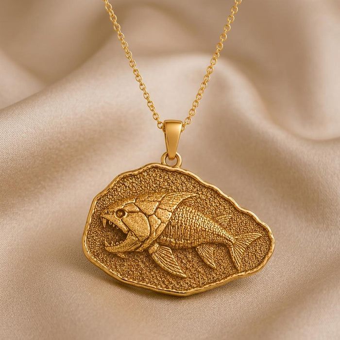 Close-up of Gold Plated Silver Dunkleosteus fish relief pendant on beige fabric