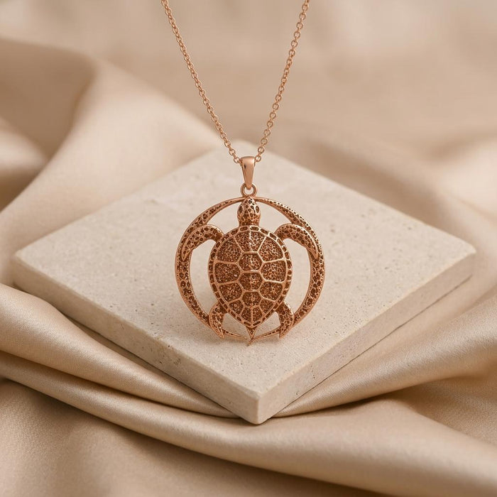 Rose Gold Plated Eclipse Turtle Relic pendant displayed on a square pale stone tile