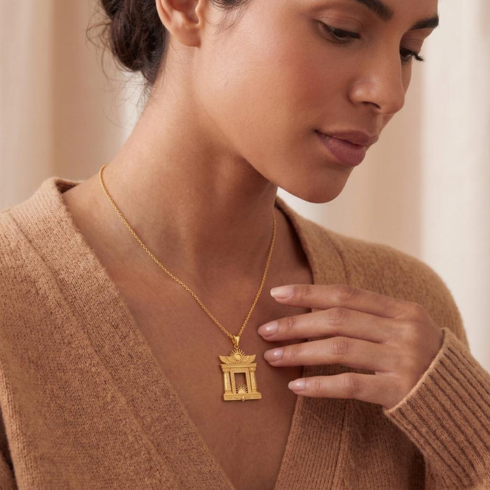 Model wearing a Gold Plated Silver Egyptian Solar Gate pendant necklace with a beige knit top