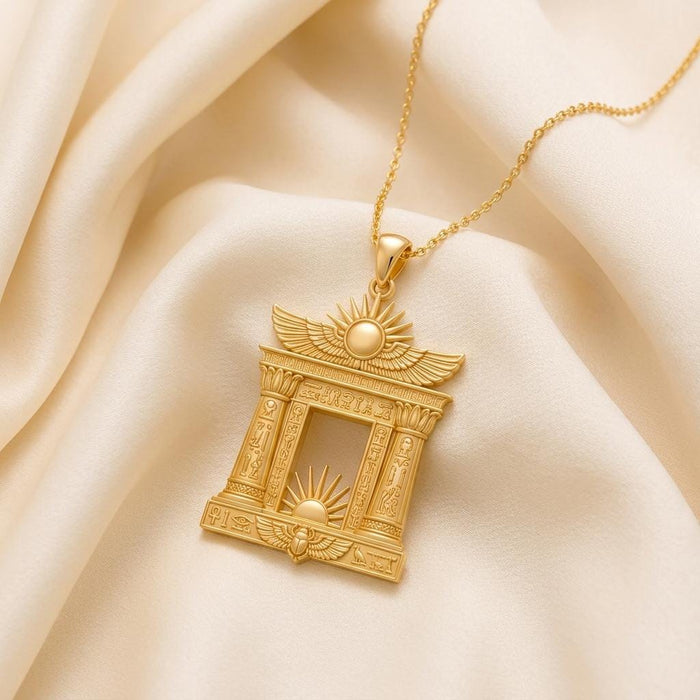 Close view of a Gold Plated Silver Egyptian Solar Gate pendant with winged sun detail on ivory fabric