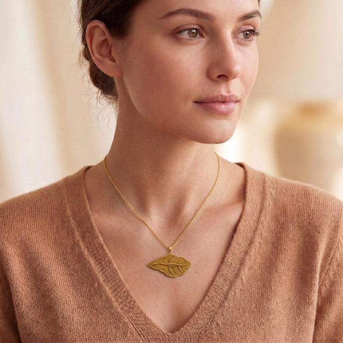 Model wearing a Gold Plated Silver Elasmosaurus Fossil Pendant necklace with a V-neck sweater